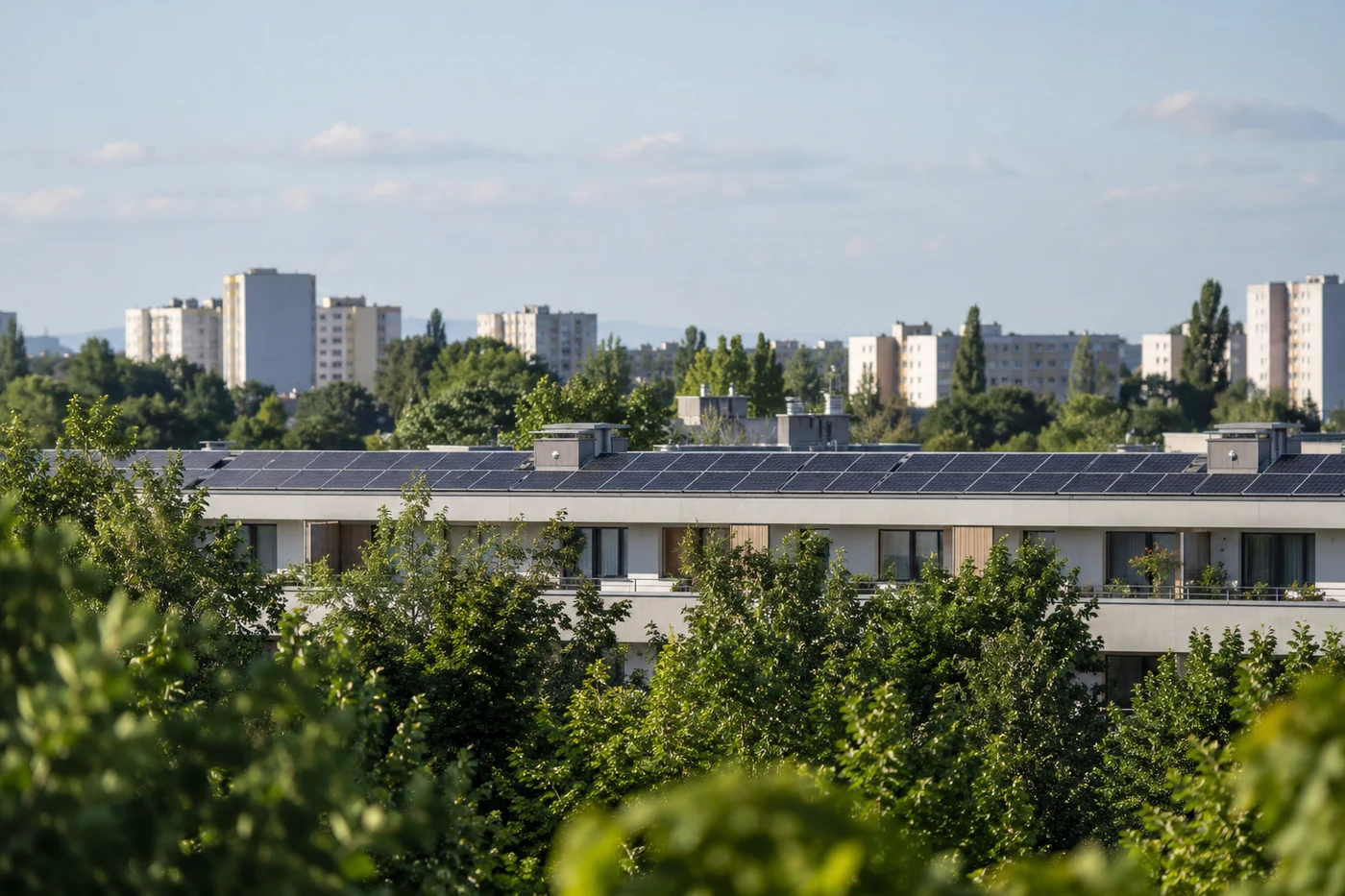 Solarmodule auf einem Wohnblock mit Bäumen im Vordergrund.
