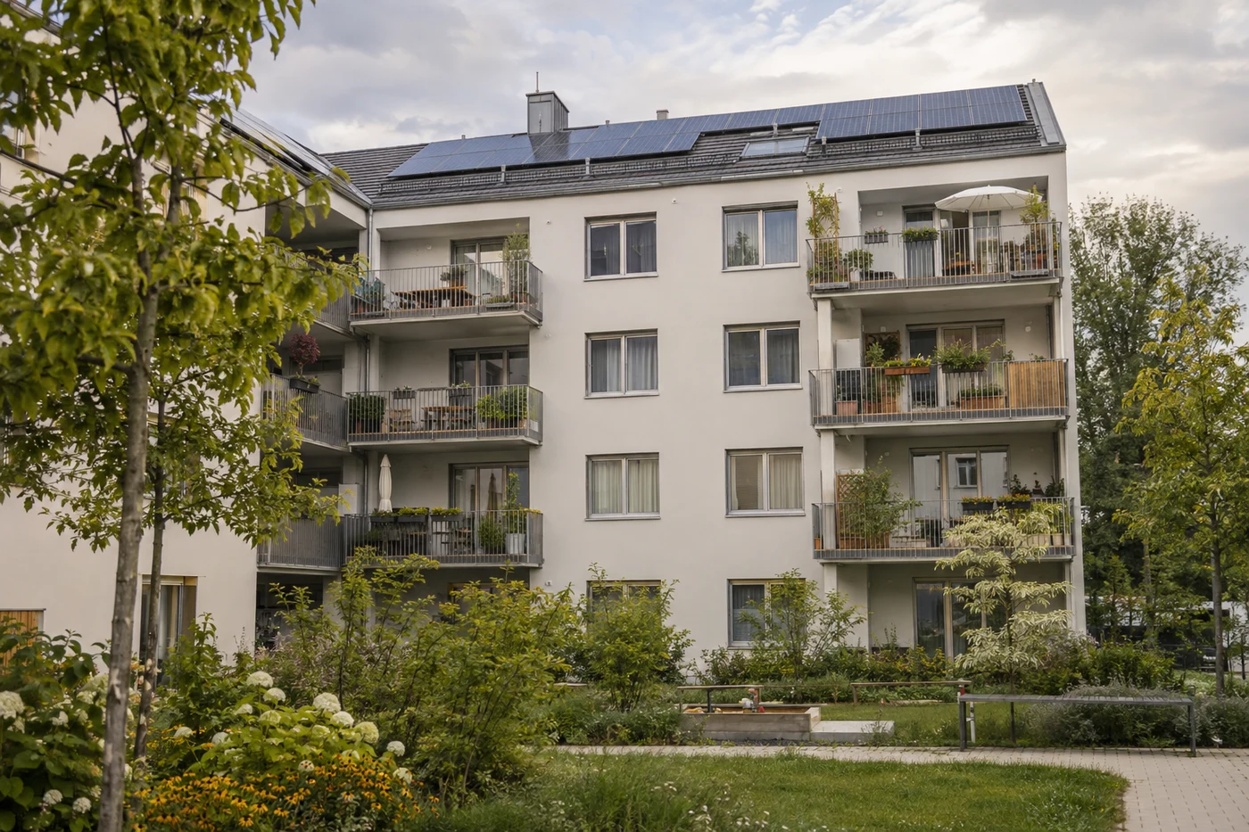 Mehrfamilienhaus mit Solarmodulen auf dem Dach und mehreren Balkonen