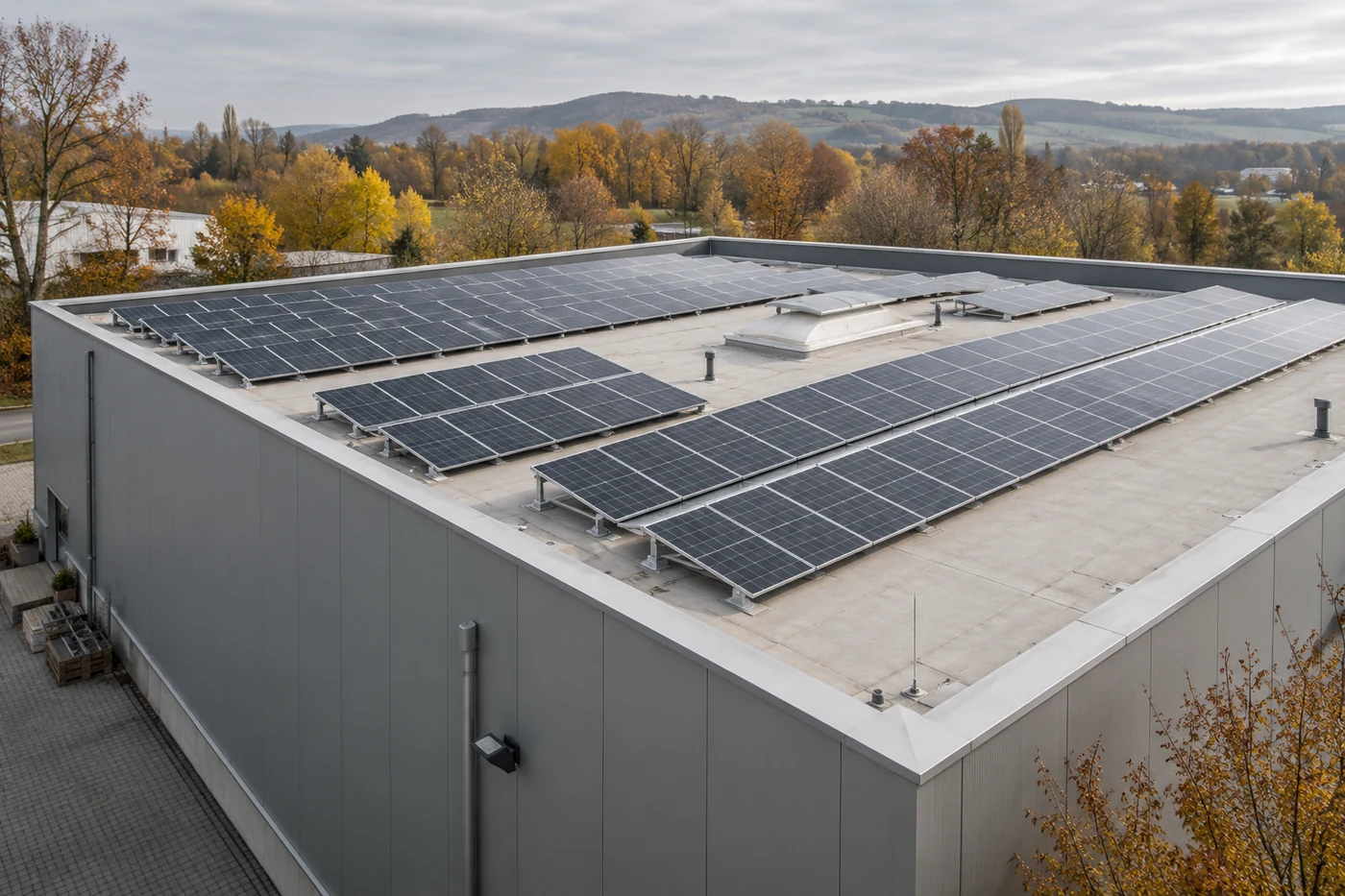 Solarmodule auf dem flachen Dach einer kleinen Gewerbehalle mit Wartungswegen.