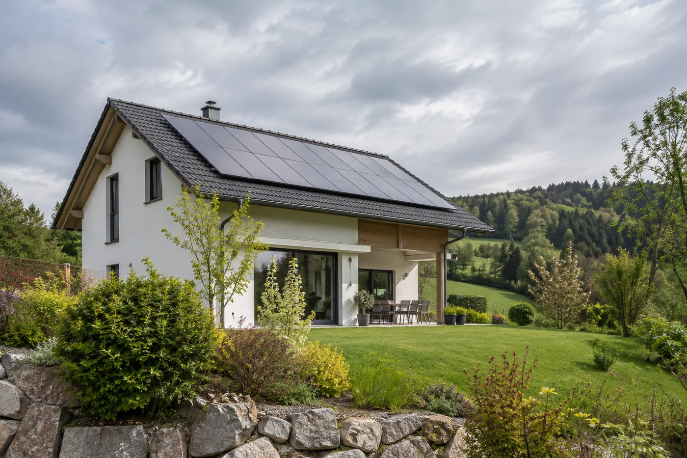 Haus mit Solarmodulen in einer hügeligen Landschaft