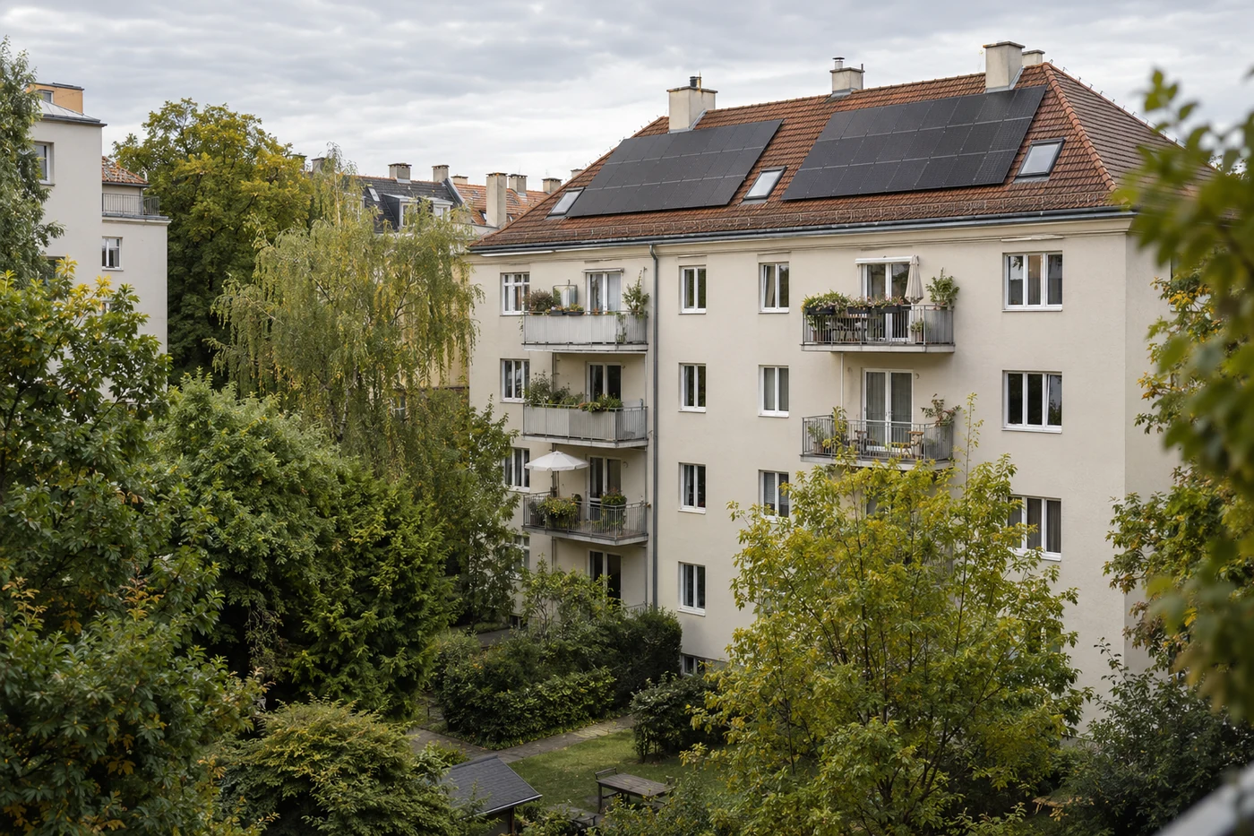 Solarmodule auf einem städtischen Wohnhaus über einem begrünten Innenhof.